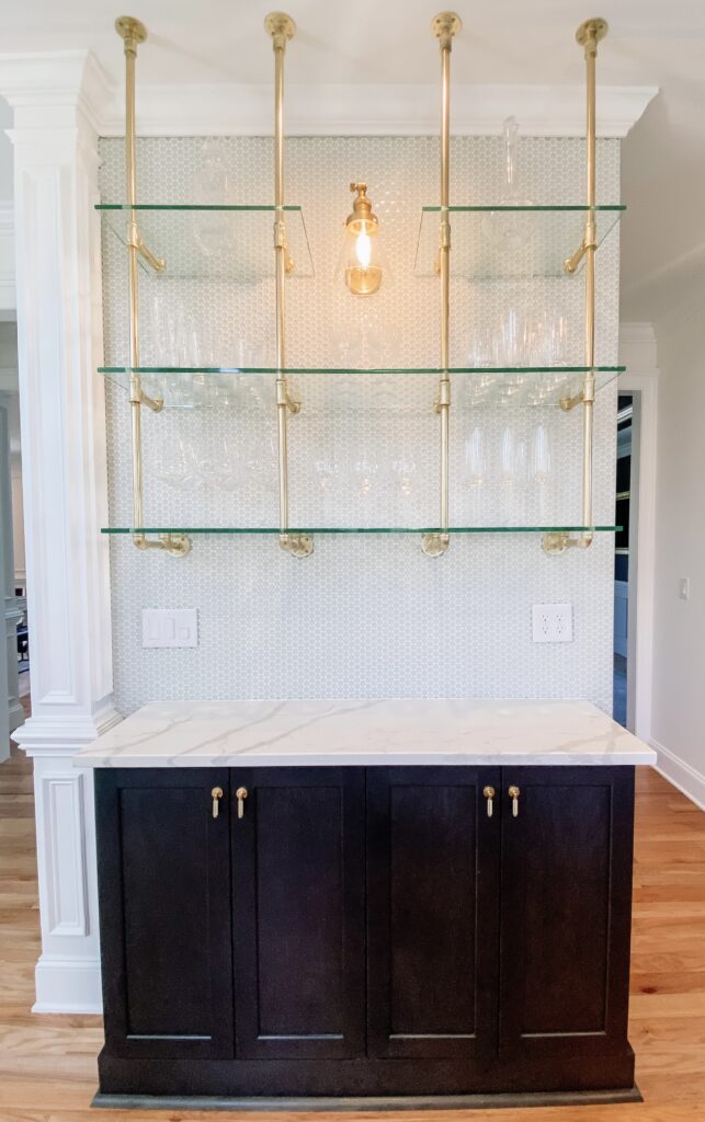 Dry bar with penny tile backsplash, open glass and brass shelving