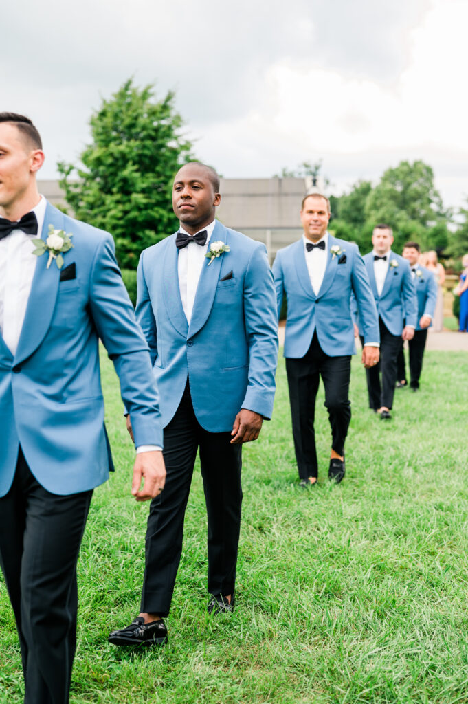 Groomsmen walking down aisle in blue tuxedos