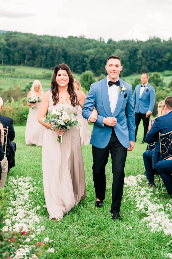 Bridesmaid and groomsmen walking down aisle in vineyard