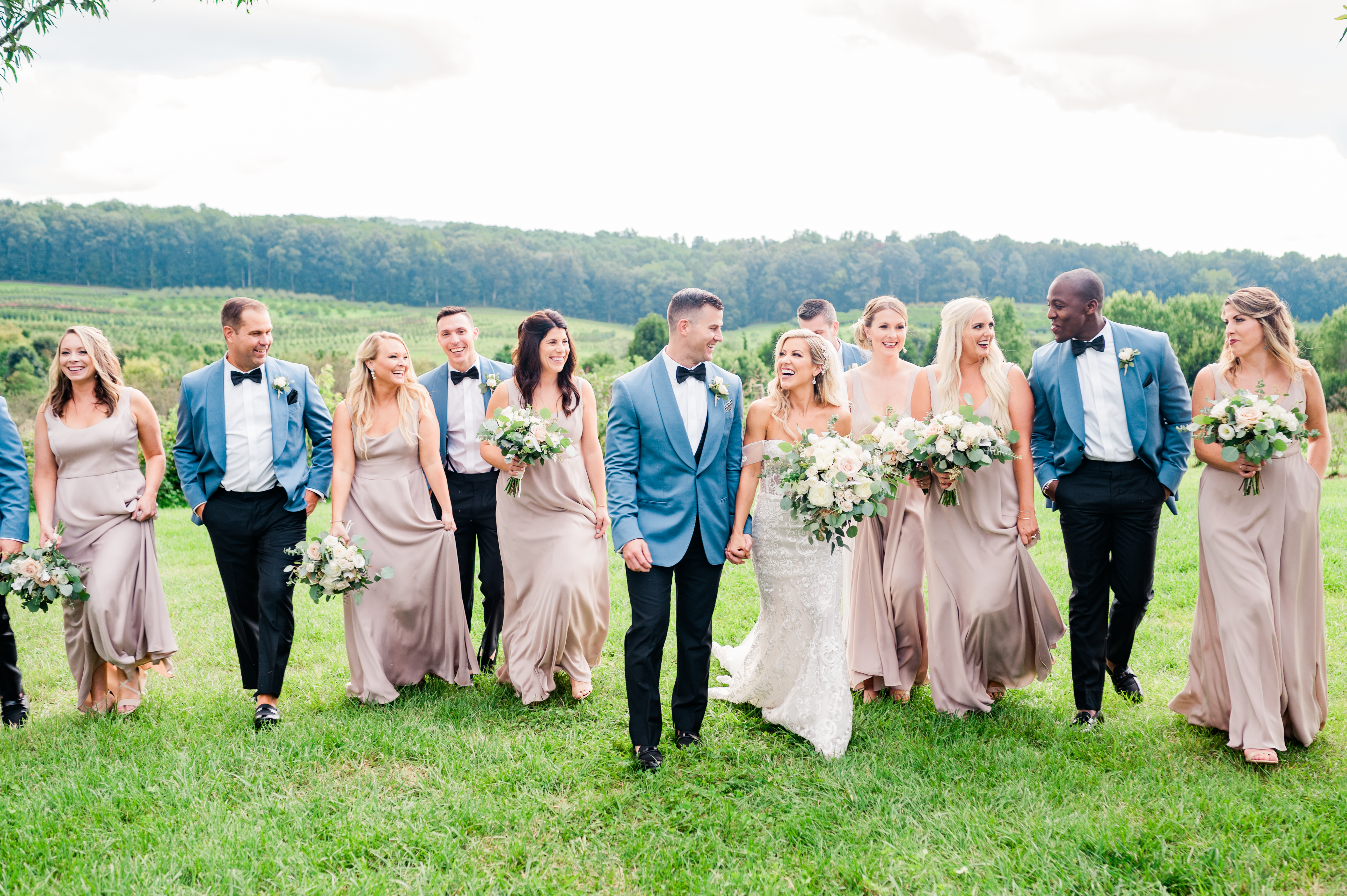 Wedding party walking outside in champagne dresses and blue tuxedos