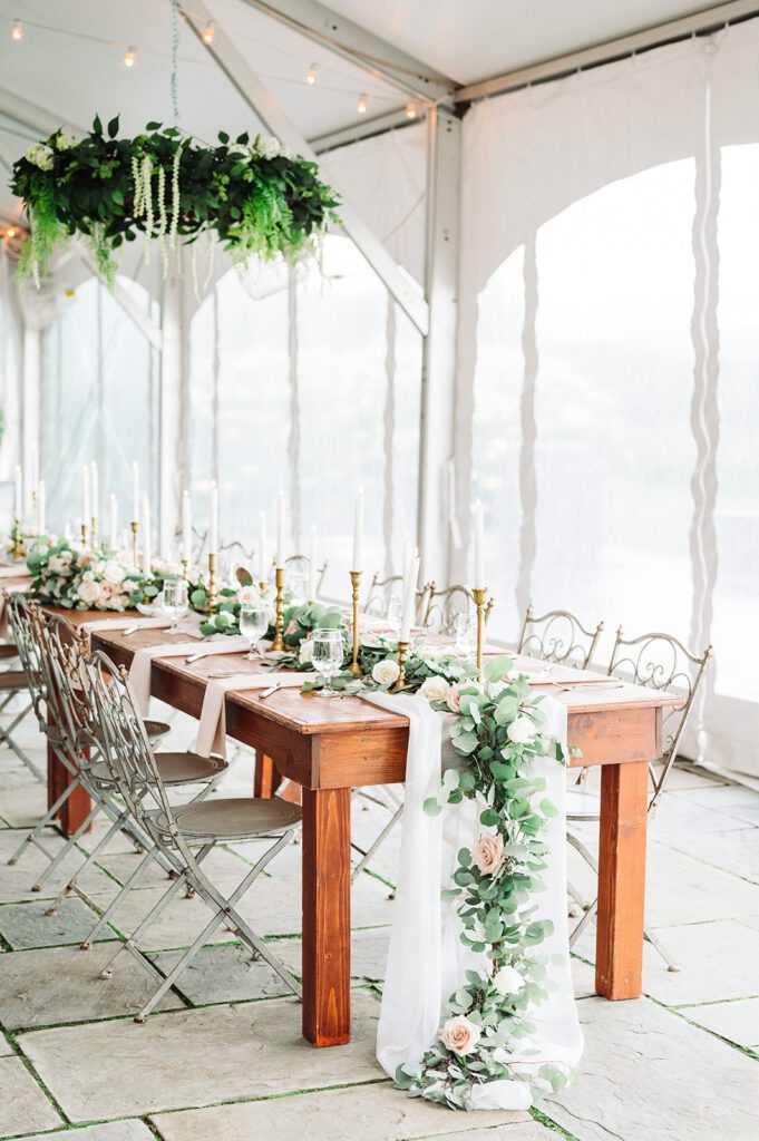 Romantic wedding reception decor - chiffon table runner with eucalyptus garland, roses, and hanging floral arrangement