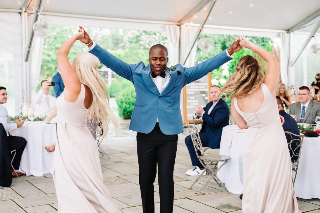 Groomsman twirling two bridesmaids around