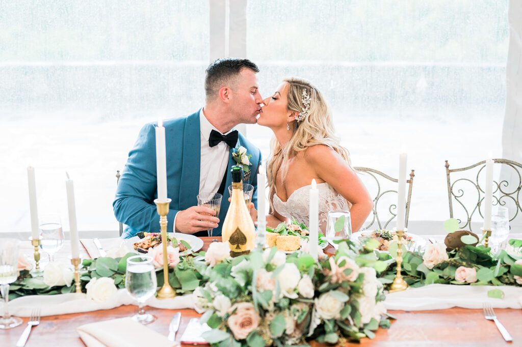 Bride and Groom kissing at head table with Ace of spaces Champagne