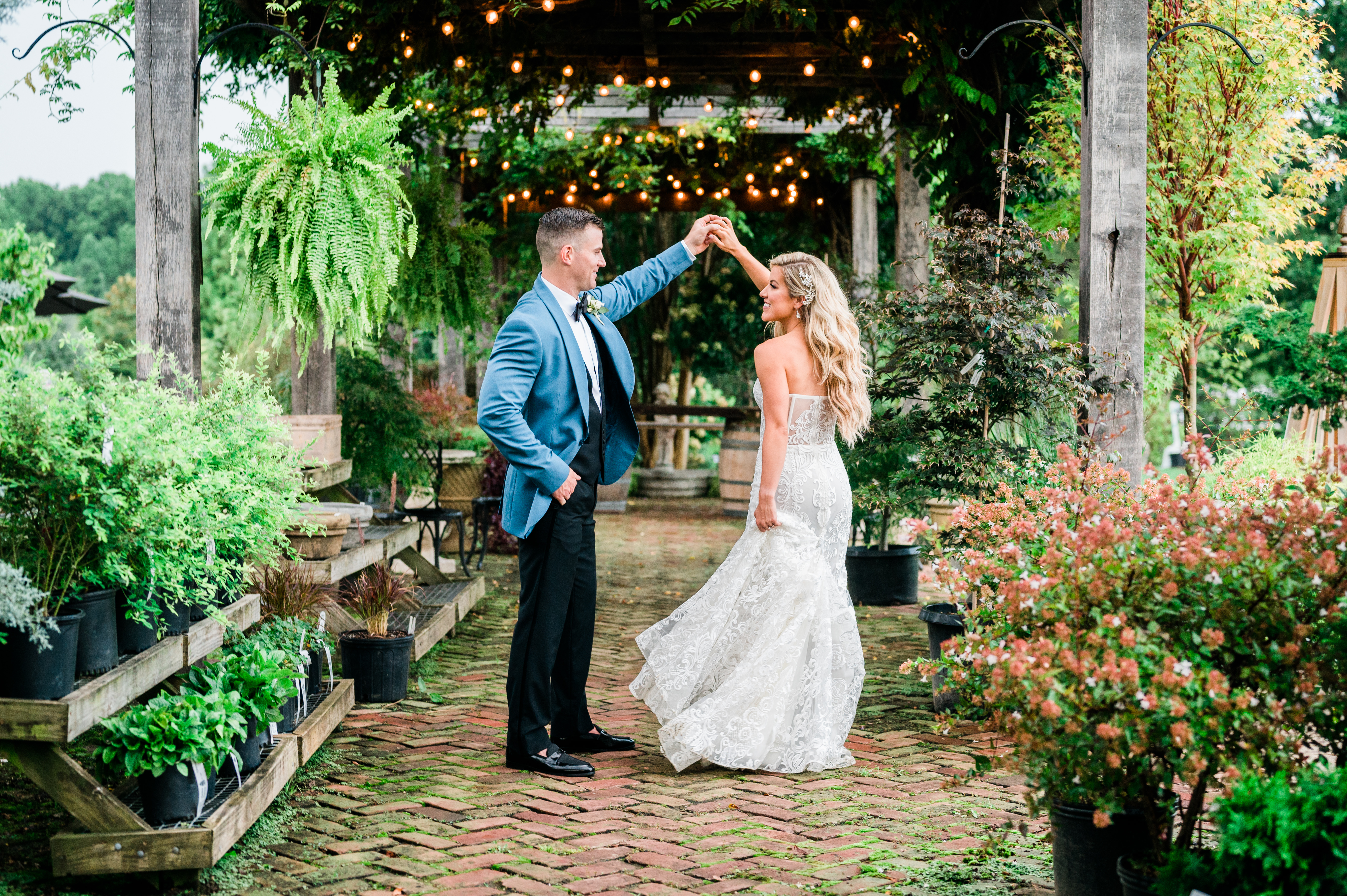 Groom twirling bride in arboretum under pergola 