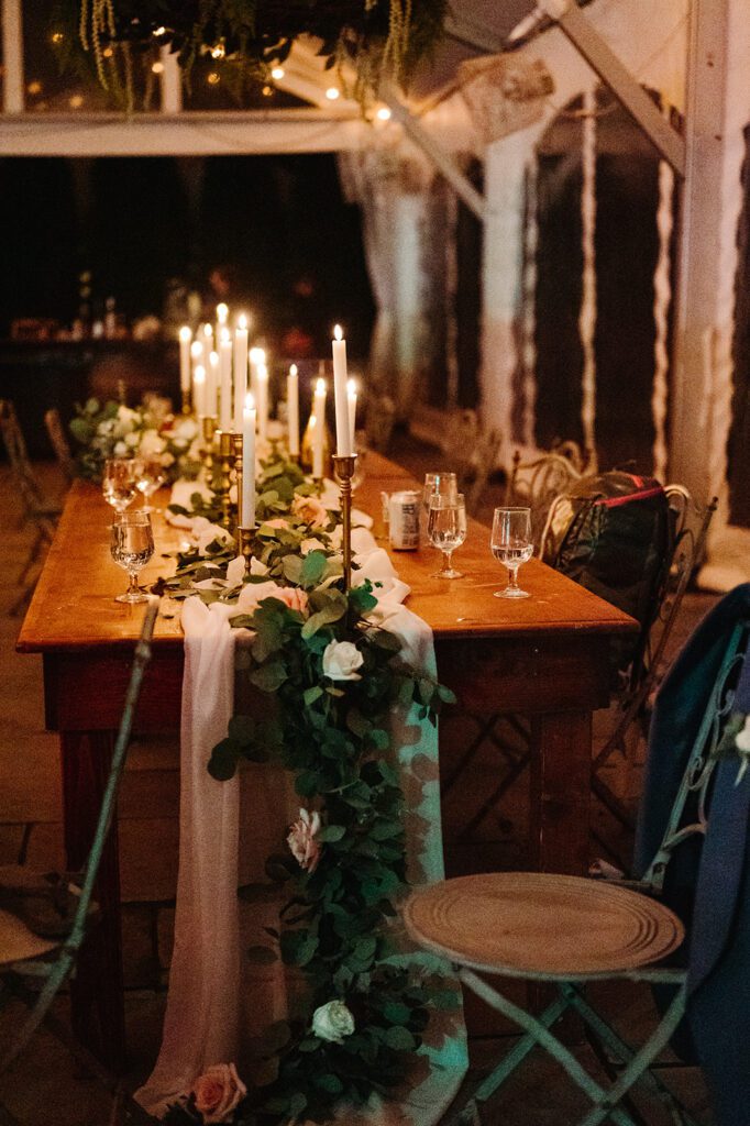 Romantic head table decor in dark with vintage candles and eucalyptus runner