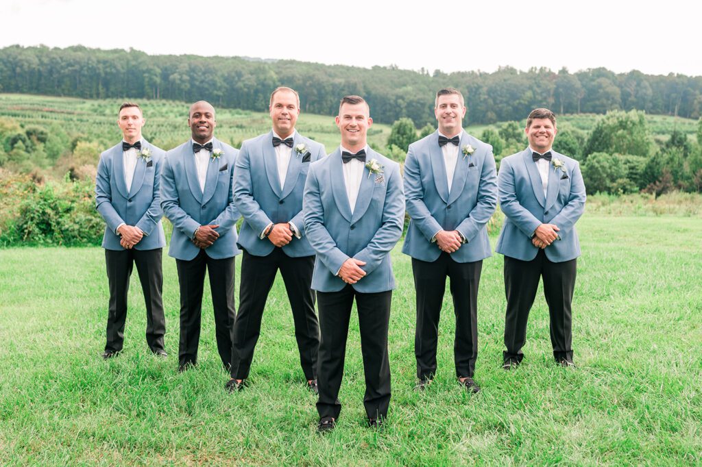 Groomsmen standing in baby blue tuxedos with black bow ties