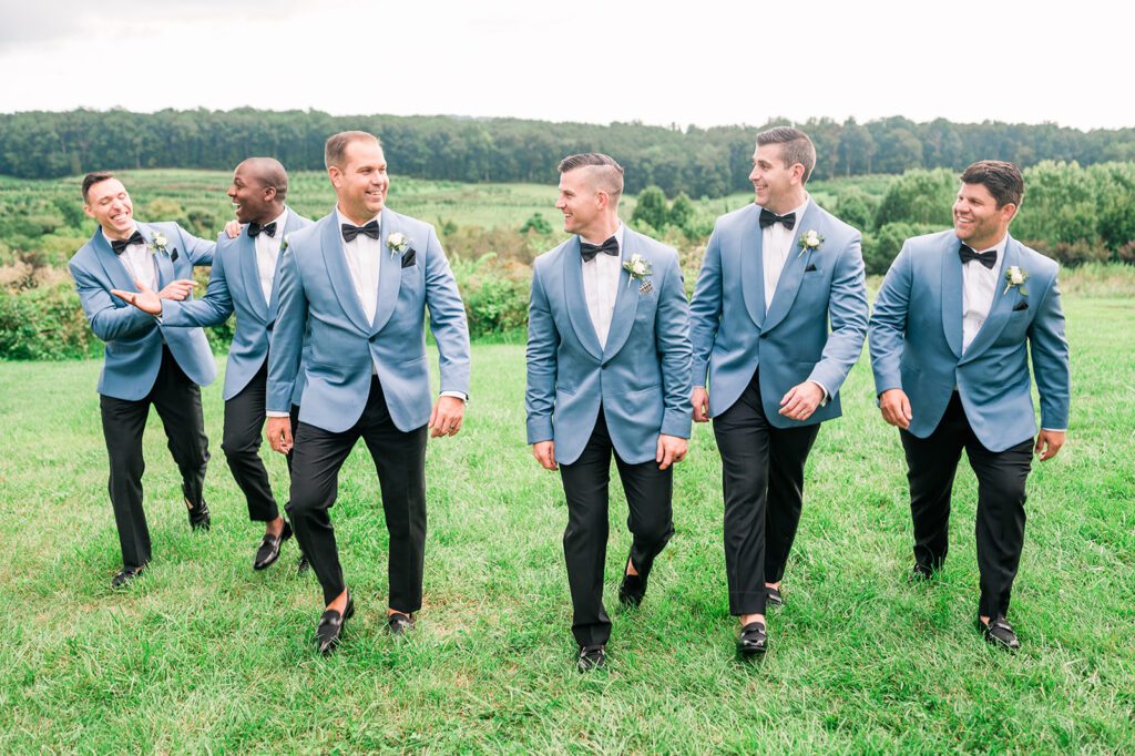 Groomsmen walking in baby blue tuxedos with black pants and black bowties